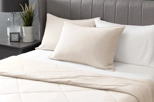 Angled view of two Cloudstone Cool Touch Pillowcases sitting at the head of a white bed.