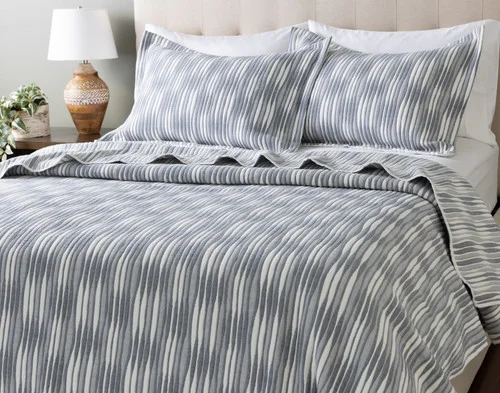 Angled view of our Tidemark Quilt Set dressed over an empty queen bed.