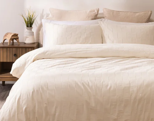 Front, off-centre view of our Obrigado Duvet Cover Set dressing a queen bed in a simple bedroom.