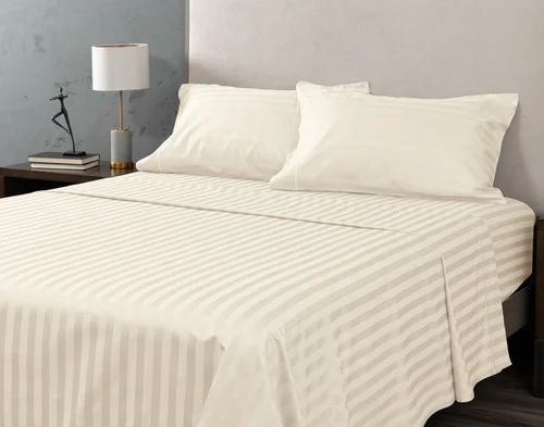 Angled view of our Cream Luxor Egyptian Cotton Sheet Set dressed over a plain queen bed.