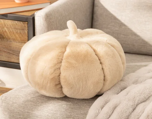 Angled view of our Pumpkin Cushion in Custard sitting politely on a beige couch.