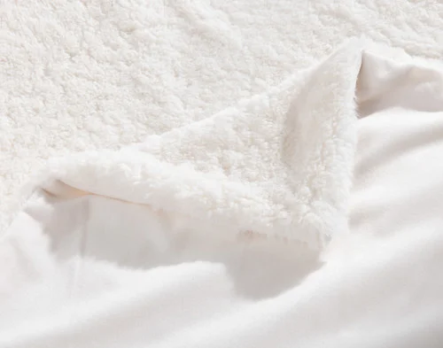 Folded corner of our Ivory Poodle Faux Fur Throw to show its front and reverse sides.