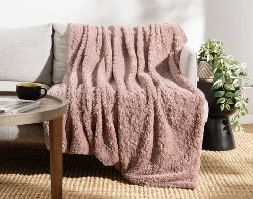 Front view of our Dusty Rose Poodle Faux Fur Throw draped over a couch.