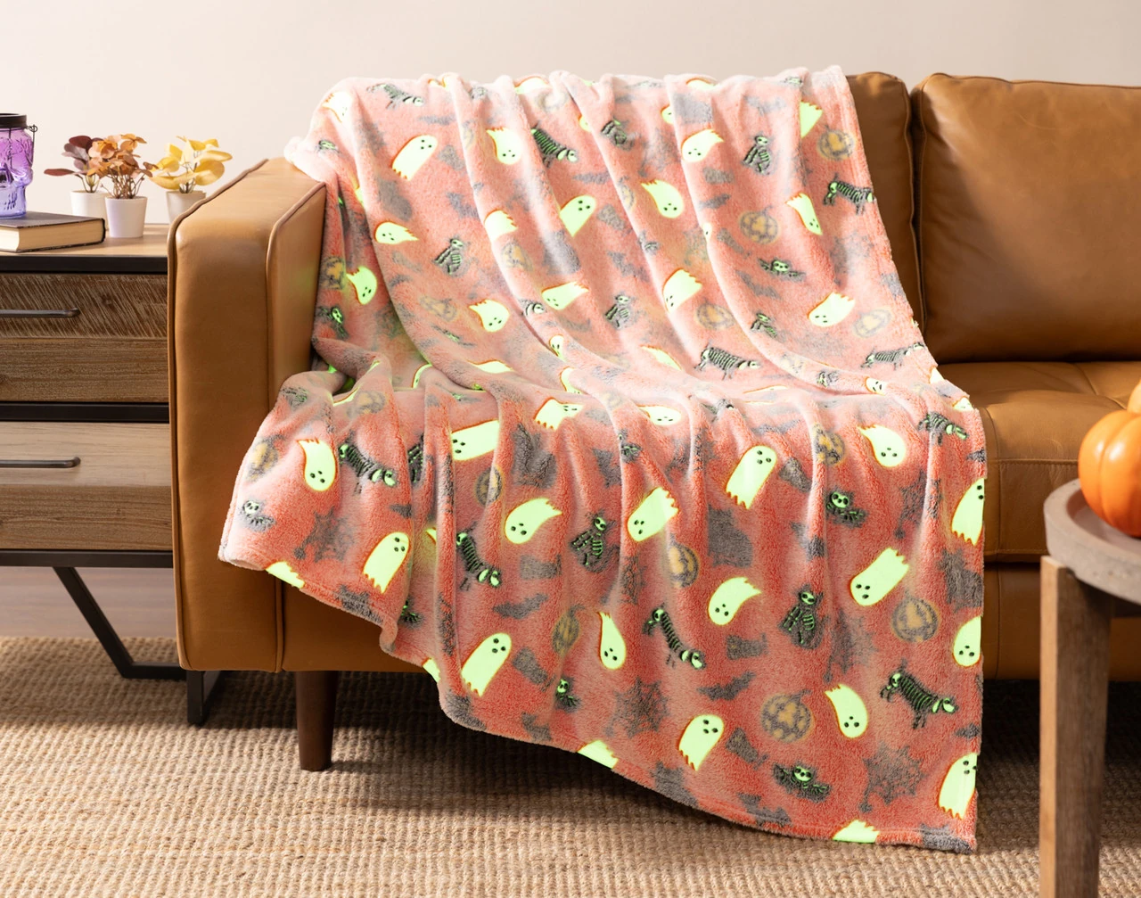 Our Boo & Bones Glow in the Dark Fleece Throw draped over a couch seat.