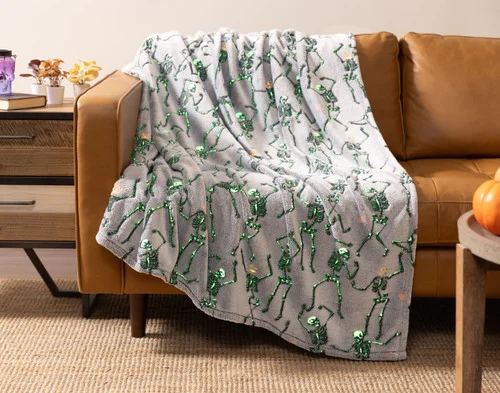 Our Skeleton Crew  Glow in the Dark Fleece Throw draped over a couch seat.