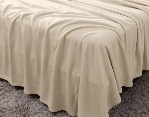 Angled view of a draped flat sheet over the corner of a bed fitted with our Cuddle Fleece Sheet Set in Oakwood.