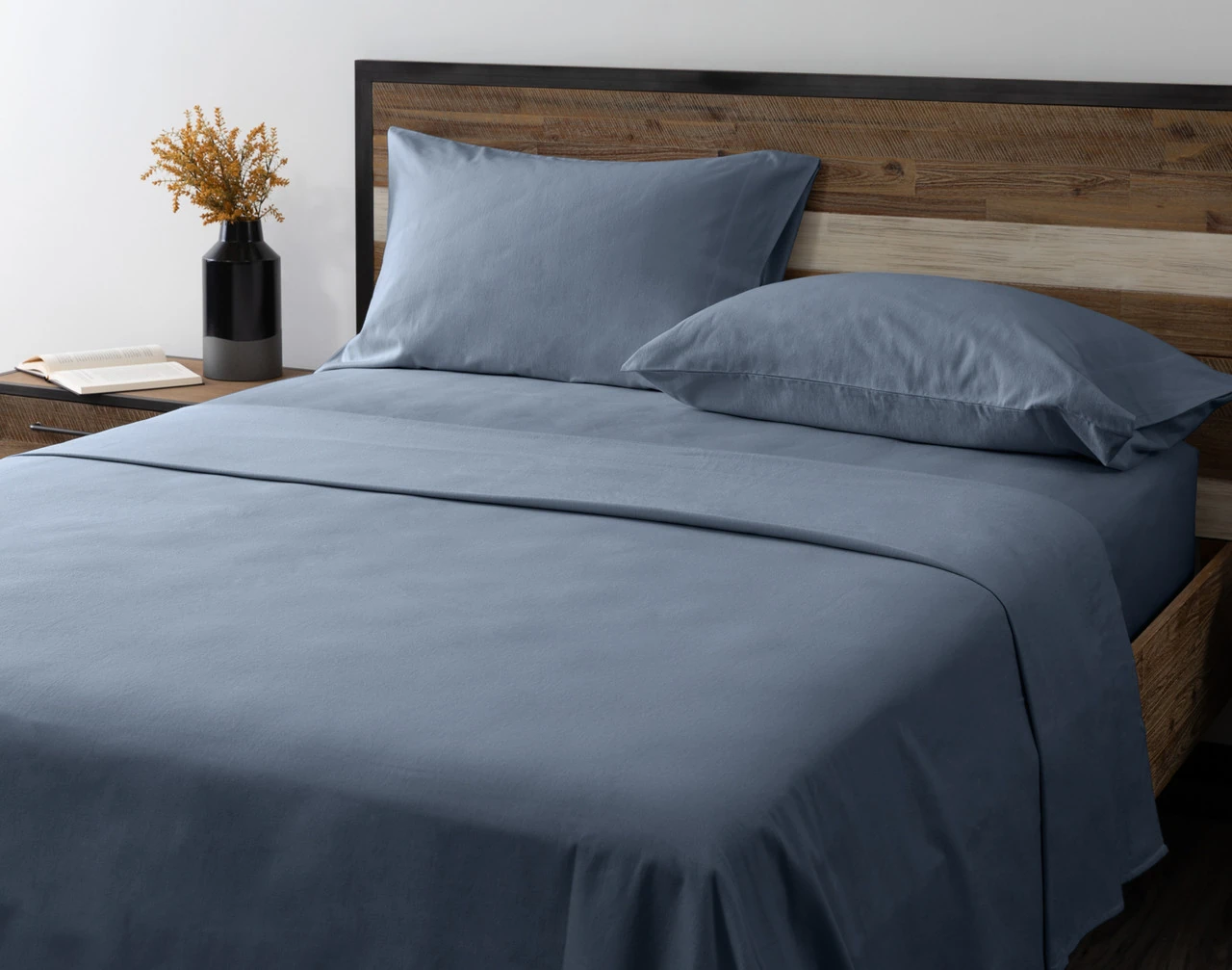 Angled view of our Arctic Slate Flannel Sheet Set dressed over an empty queen bed.