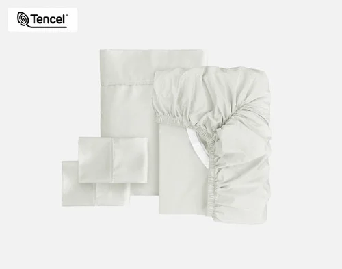 The full contents of our Eucalyptus Luxe Sheet Set in Oyster sitting against a solid background, including a fitted sheet, flat sheet, and two pillowcases.
