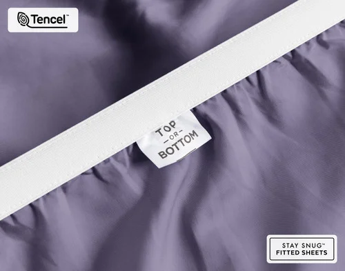 Close-up on the stretched elastic edge and tag stating "Top / Bottom" on our Eucalyptus Luxe Fitted Sheet in Purple Basil.