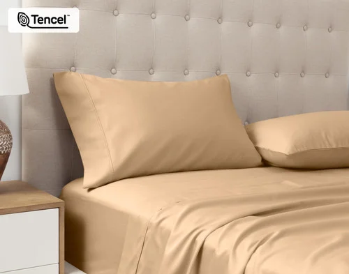 Angled view of our Eucalyptus Luxe Pillowcases in Sandalwood sitting against a headboard of a beige queen bed.
