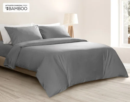 Angled view of our Deep Charcoal Bamboo Cotton Duvet Cover Set dressed over a queen bed in a bright bedroom.