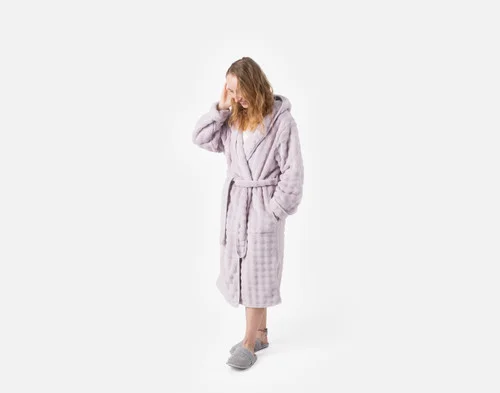 Woman posing in our Sage Mini Bubble Hooded Bathrobe standing in a white room.