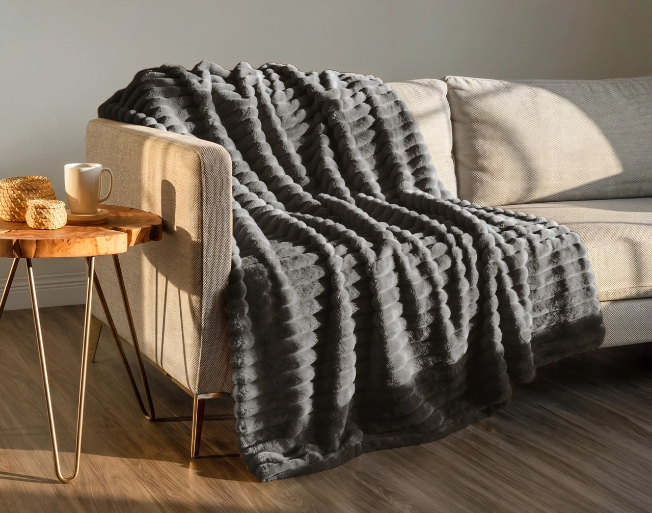 Our Channel Plush Throw - Dark Slate draped against a grey couch.