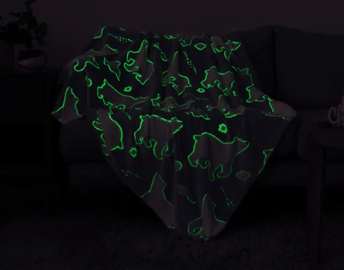 Dark view of our Polar Cove Glow in the Dark Throw showing its green-outlined designs.