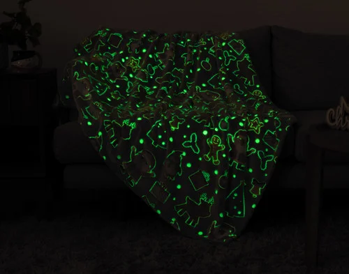 Dark view of our Frosted Fun Glow in the Dark Throw showing its green-outlined designs.
