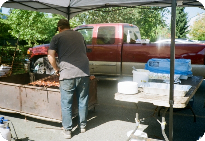 Un cuisinier de Henry's Outdoor BBQ fait griller de la viande lors d'un barbecue d'anniversaire à l'extérieur du siège social de QE Home.