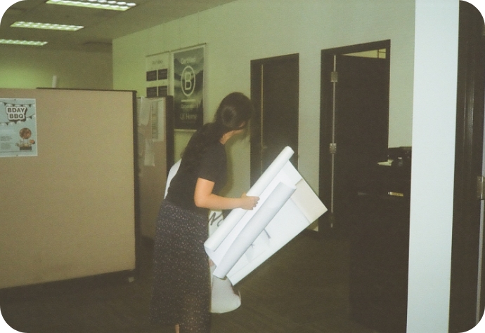 Un graphiste de QE Home gère plusieurs panneaux imprimés dans le bureau, avec une affiche du magasin B Corp visible à l'arrière-plan.