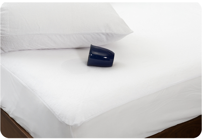 Tasse bleu foncé couchée horizontalement sur le côté sur un matelas blanc avec protège-matelas.