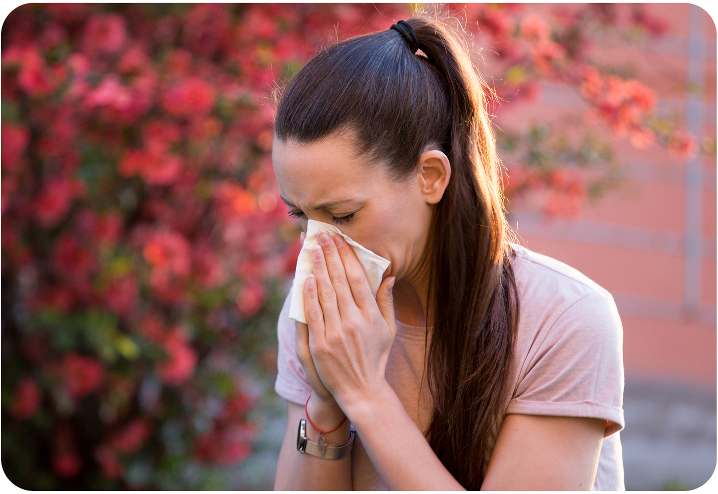 Woman blowing her nose into tissues during peak allergy season