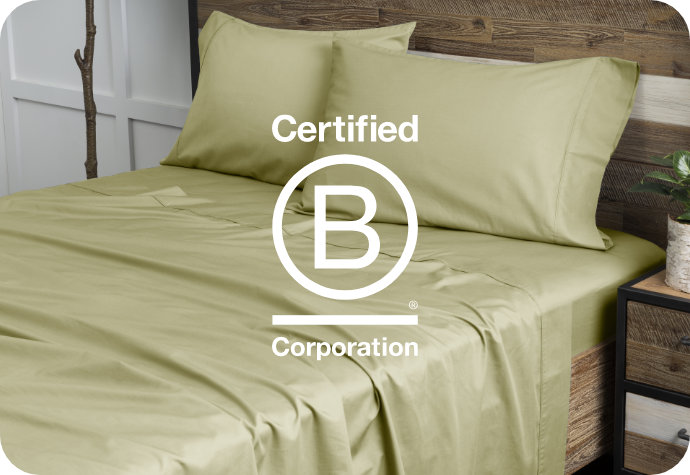 B Corp logo over a bed dressed in QE Home sheets.