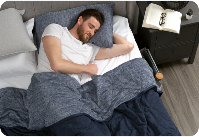 Homme barbu dormant dans un lit blanc et bleu avec notre couverture et notre taie d'oreiller Cool Touch.