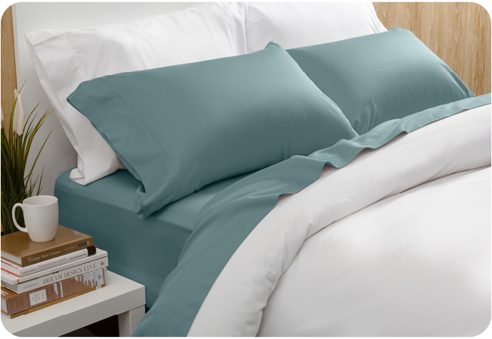 Notre Eucalyptus Luxe drap ensemble  en bleu Tidewater habillé sur un lit blanc dans une chambre en bois.