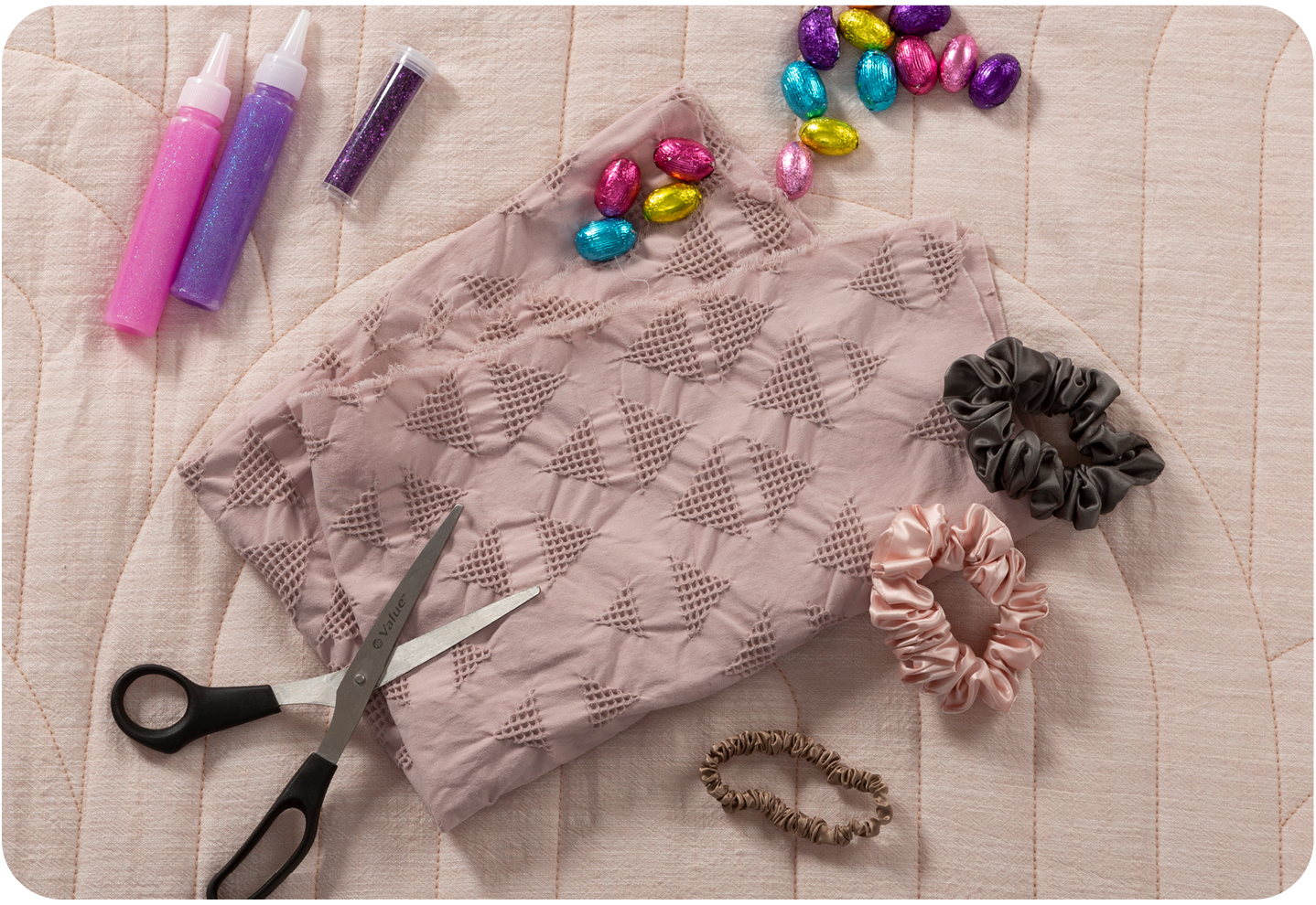 Overhead shot of the various things you can use to make your DIY rabbit, including fabric, scissors, scrunchies, and glitter glue.