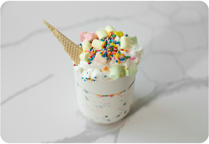 Side view of the horned and sugary sweet Unicorn Hot Chocolate in a sparkly colourful travel cup.