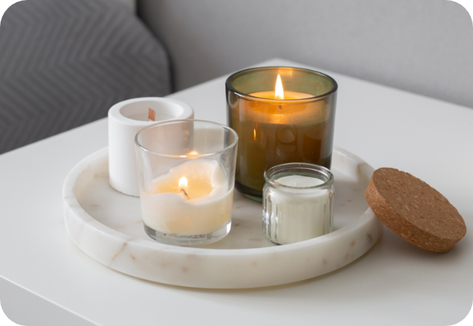 A collection of candles atop a small marble tray on a white bedside table.