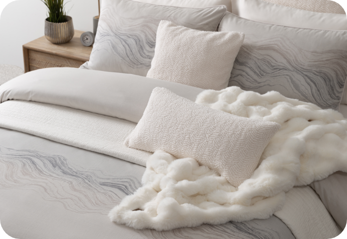 A cozy bed dressed with the Striation Duvet Cover and Pillow Shams and a Bubble Faux Fur Throw.