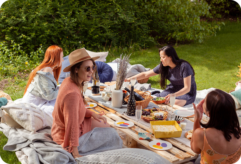 People sitting at a picnic surrounded by QE Home bedding and accessories.