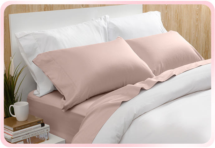 Notre Bamboo Cotton drap  ensemble  en rose blush est représenté sur un lit blanc.