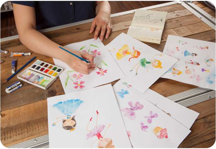 Une femme est représentée en train de peindre des illustrations colorées sur du papier blanc.
