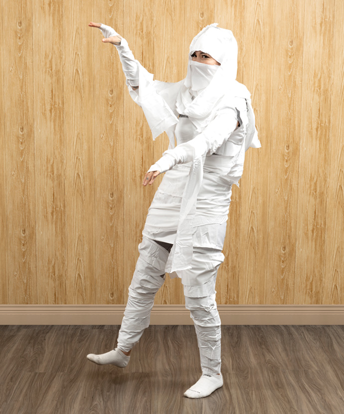 Woman dressed in a mummy costume made from white fabric scraps. Woman dressed in a mummy costume made from white fabric scraps.