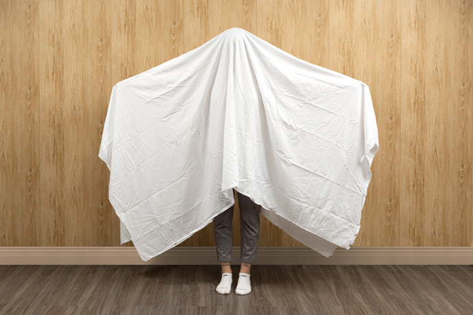 Womanwith a full white flat sheet draped over her head to show its size. Womanwith a full white flat sheet draped over her head to show its size.