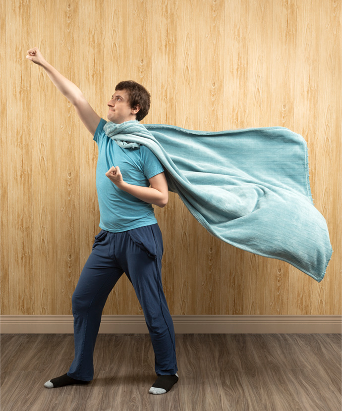 Boy in bright blue pajamas and a soft throw blanket wrapped around his neck as a cape. Boy in bright blue pajamas and a soft throw blanket wrapped around his neck as a cape.